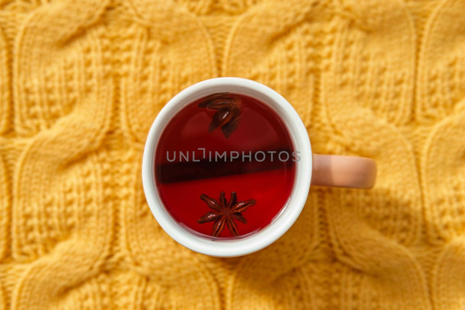 Karkade tea in an orange cup on an orange knitted background. The concept of the autumn season, natural colors. Red fruit tea.