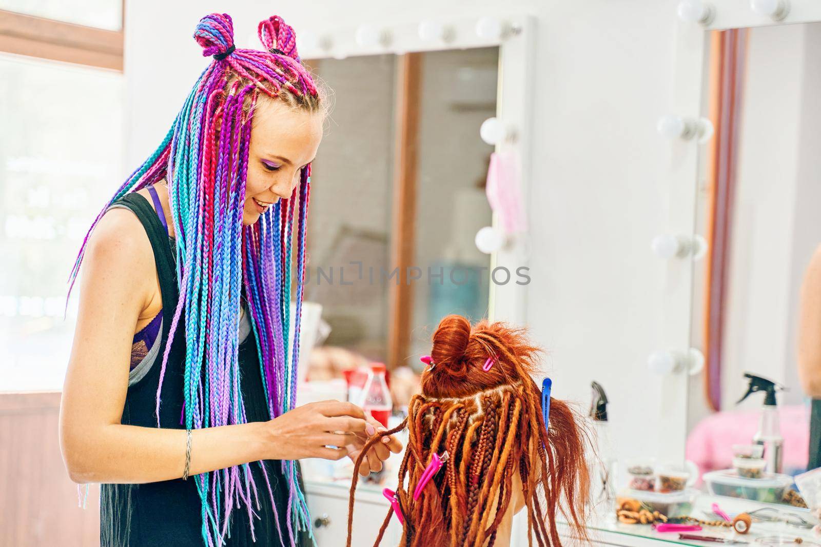 Woman hairdresser weaves to girl ginger dreadlocks. by savconstantine