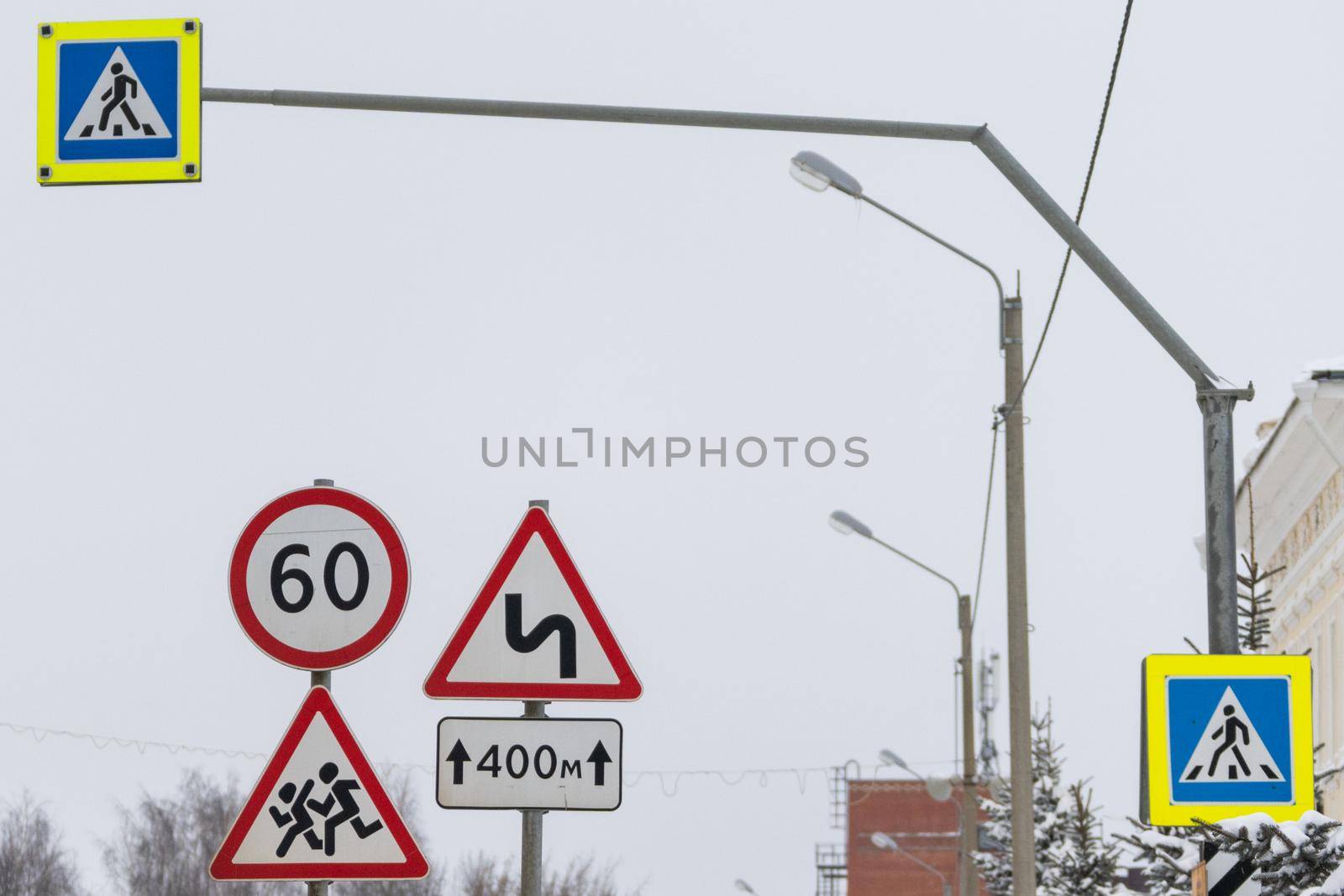 three road signs stand side by side. a sign Overtaking is forbidden, the speed limit sign. the sign indicates that the road has turns for several hundred meters. pedestrian crosswalk signs with night lighting weigh on a special pole