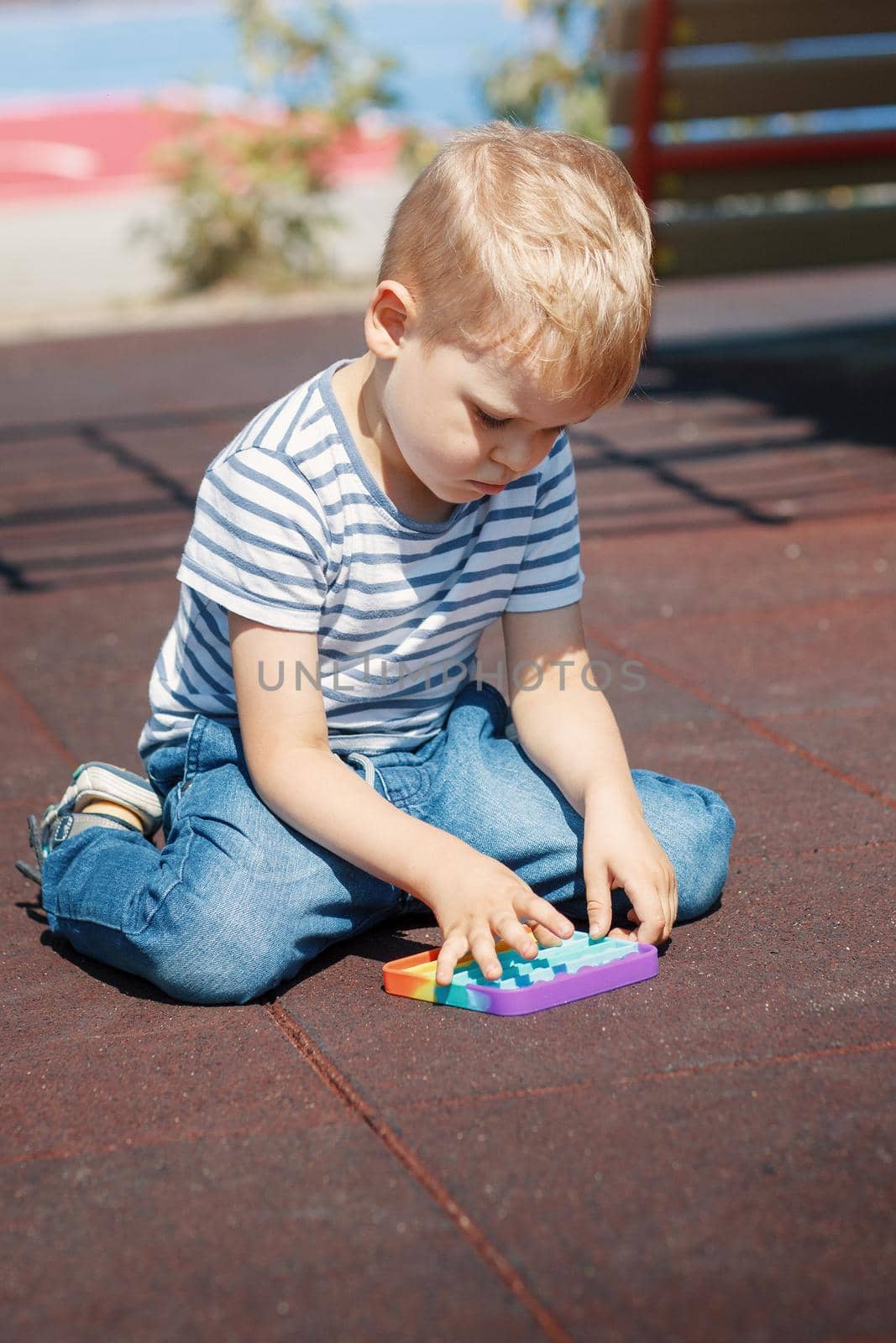 The child kneels on the floor of the playground and plays with a colourful toy for relaxation.