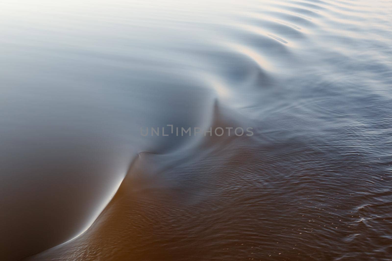 Footprint of the ship. Water twisted by a boat propeller. Beautiful water surface texture. Horizontal photo