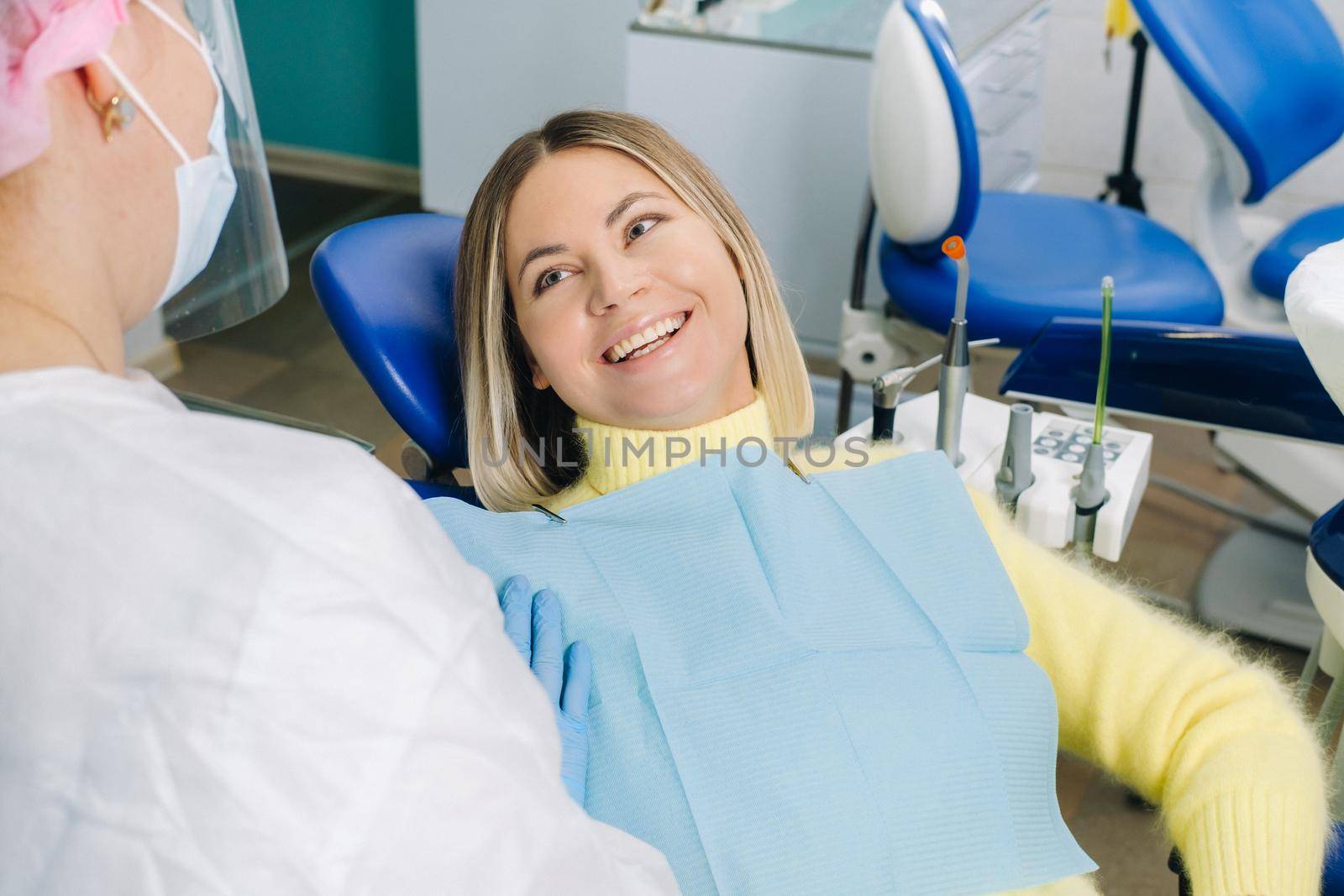 The girl smiles at the dentist and looks at her.