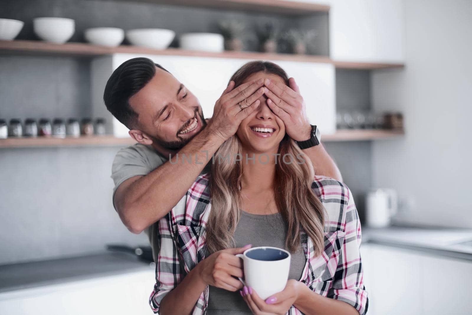 happy man joking with his girlfriend in the kitchen in the morning by asdf