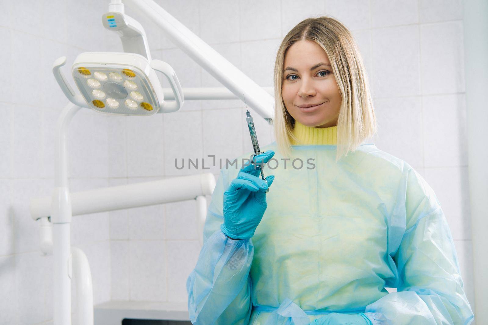 The dentist holds an injection syringe for the patient in the office.