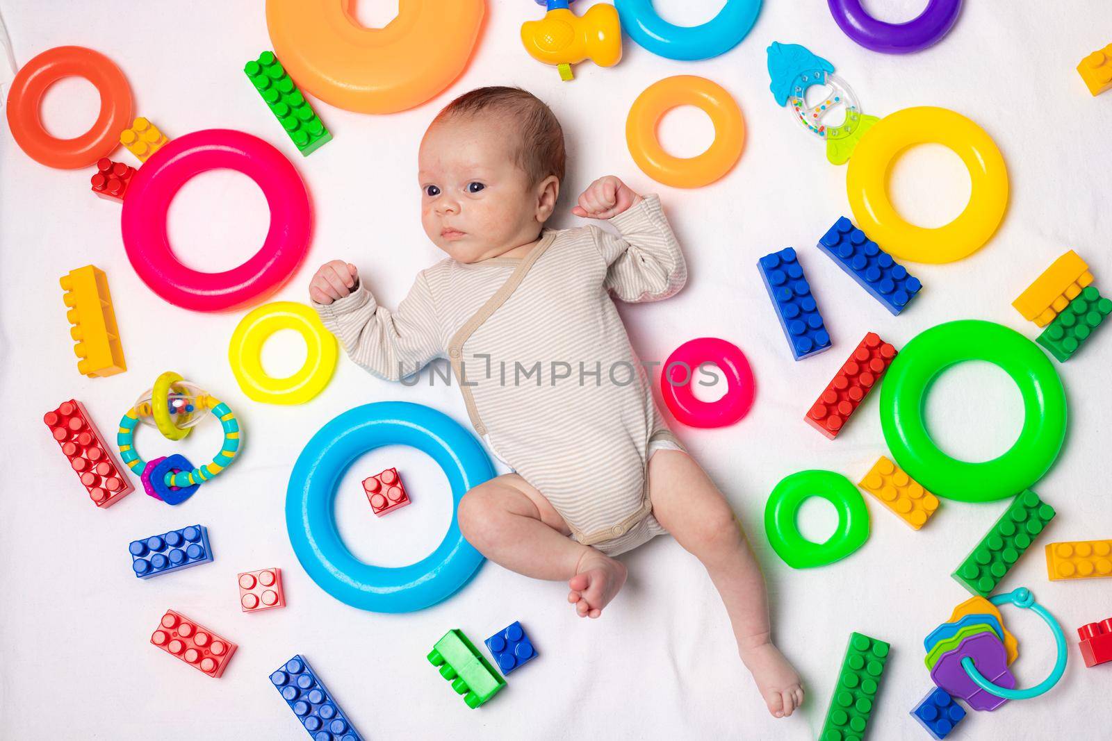 The baby is lying in toys . An article about children's toys. A selection of toys for kids. Designer