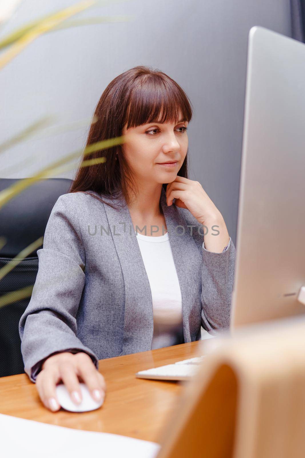 A brunette woman at a computer in the workplace. Business concept. by Annu1tochka