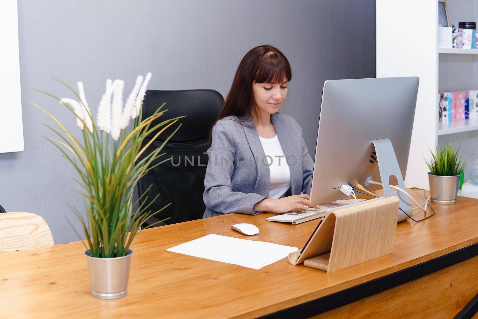 A brunette woman at a computer in the workplace. Business concept.