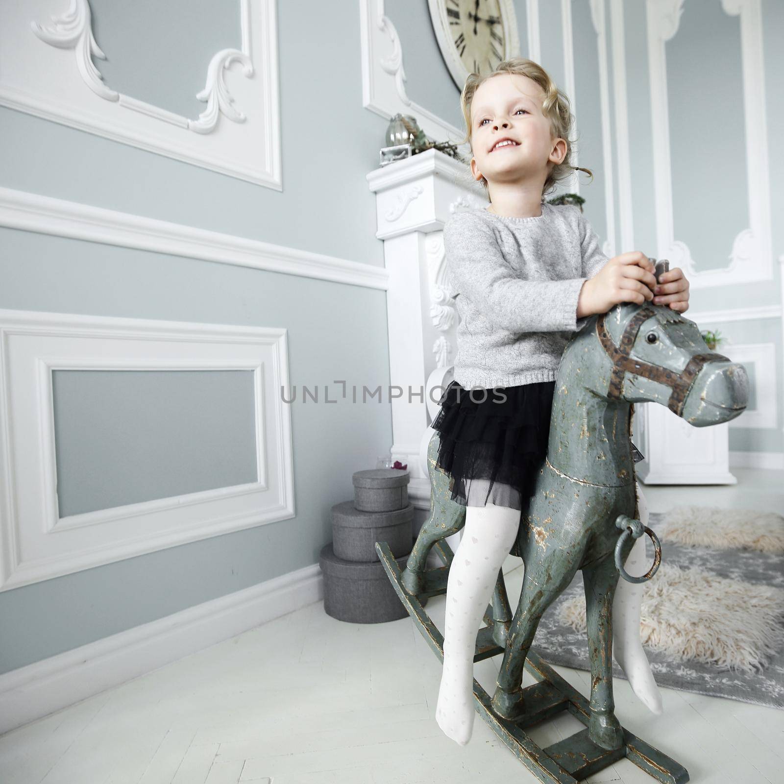 little girl playing with a wooden horse in the bedroom of the parents