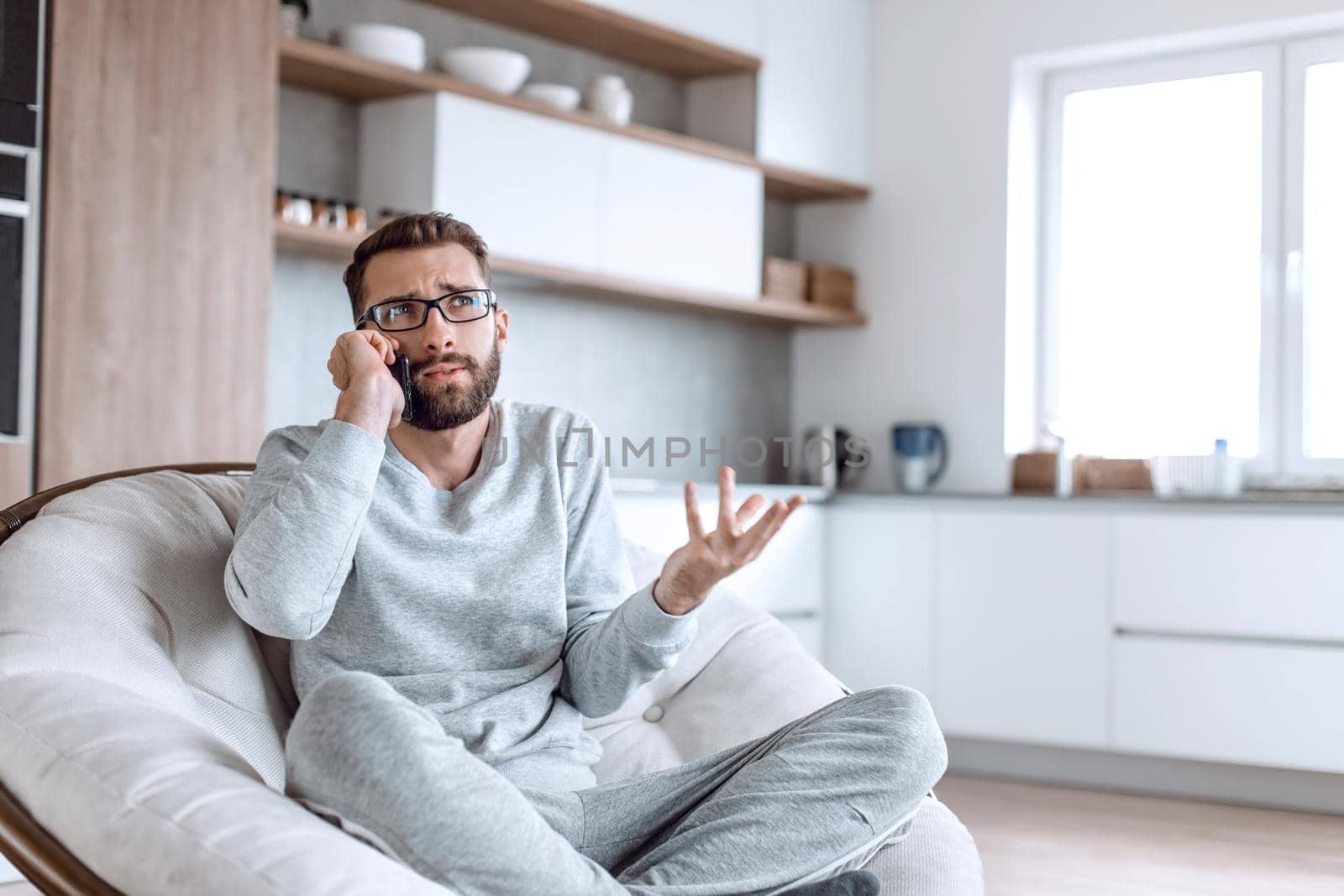cheerful man talking on a mobile phone sitting in a comfortable chair by asdf