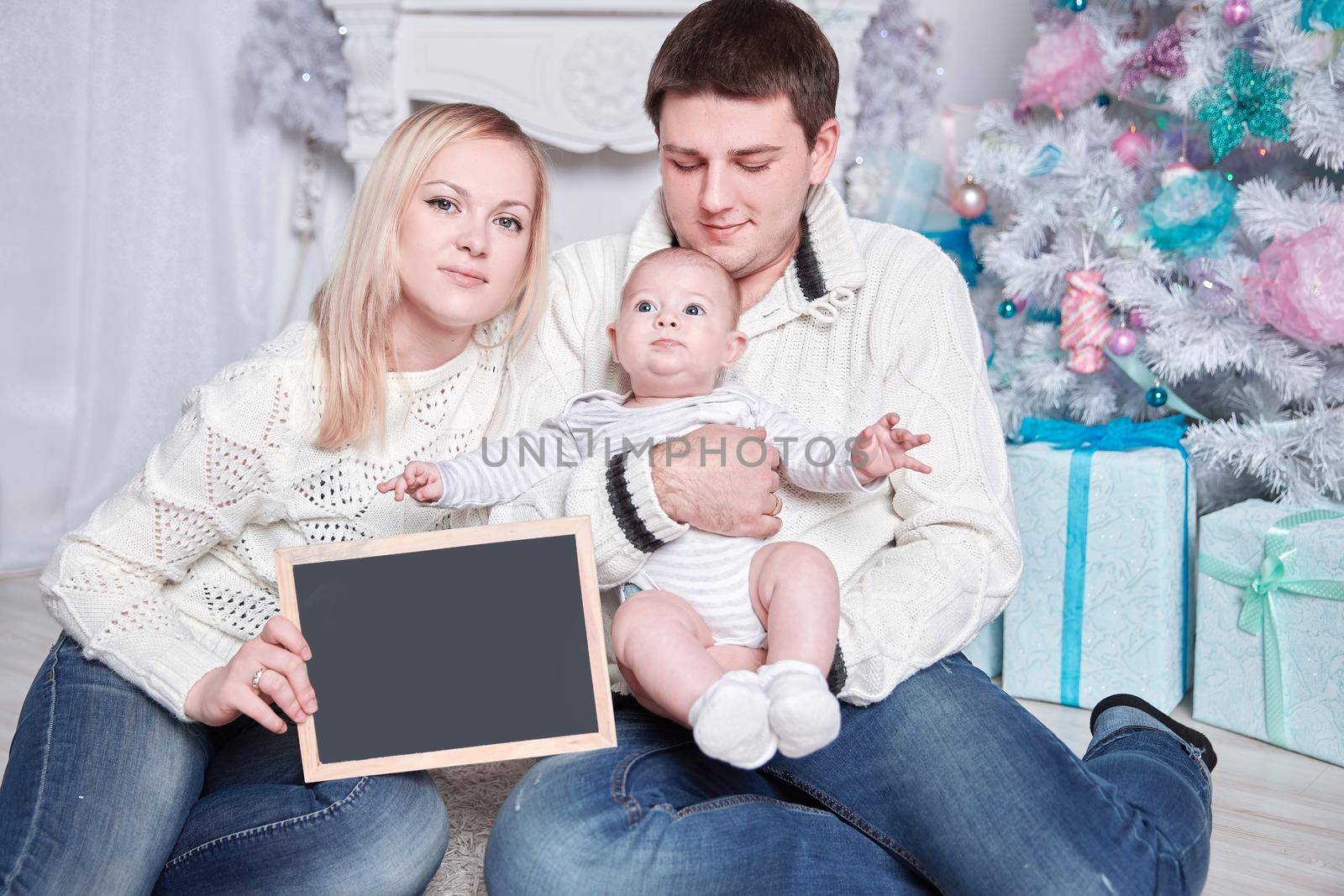 happy family holding a blank Christmas card, sitting on the carpet in a cozy living room . photo with copy space