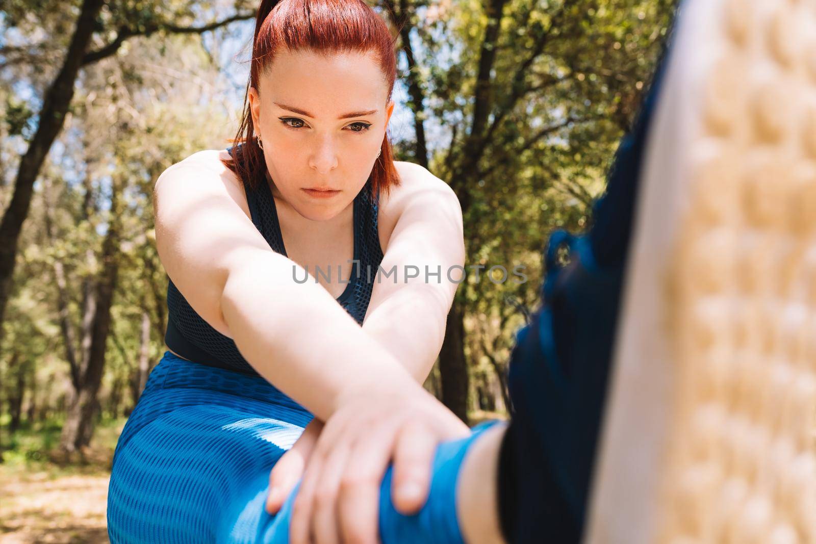 young woman practising stretching exercises for the sports championship. sportswoman preparing for a marathon. health and wellness lifestyle. by CatPhotography