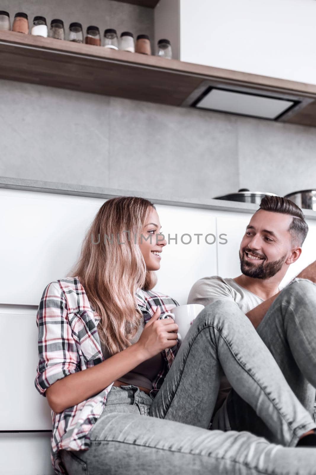 young couple drinking coffee sitting on the kitchen floor by asdf