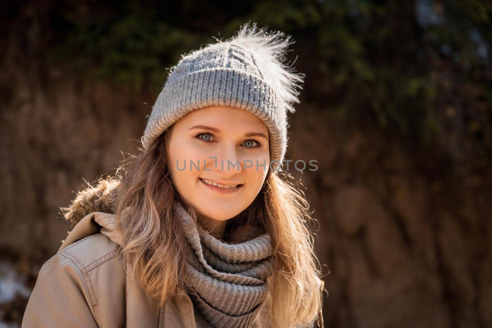Autumn portrait of caucasian blond young smiling woman in grey sweater and beanie hat outdoor by Rom4ek