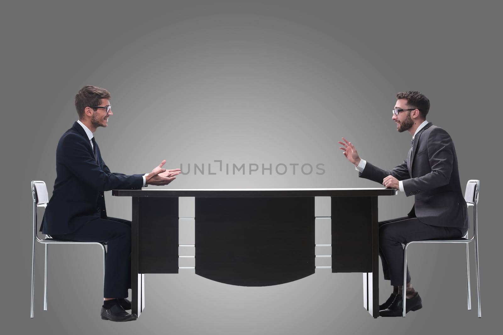 side view. two business people discussing something sitting at the table . isolated on white background