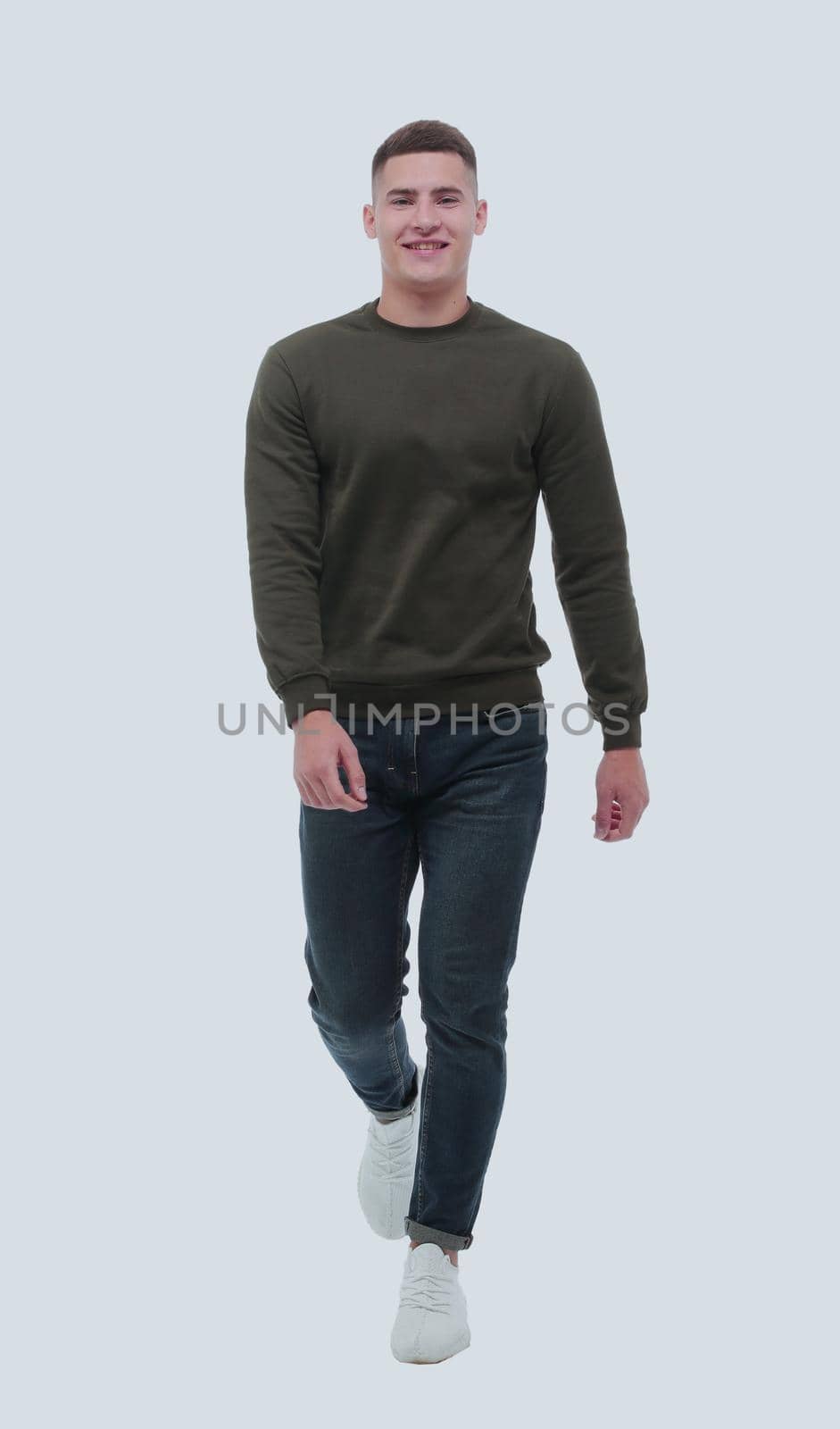 in full growth. a confident man in jeans walks forward . isolated on white