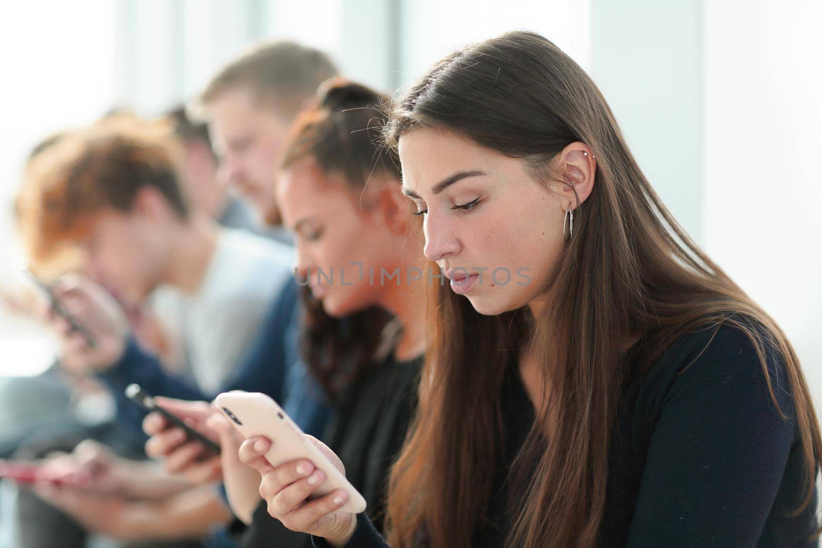 group of serious young people looking at their smartphone screens by asdf