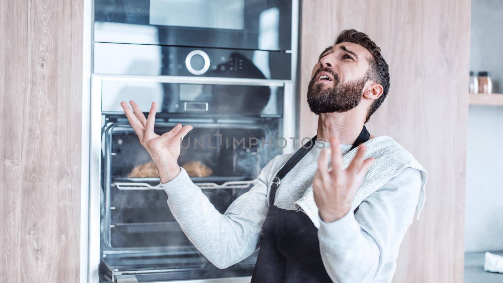 surprised man standing near the oven with burnt croissants. photo with copy space