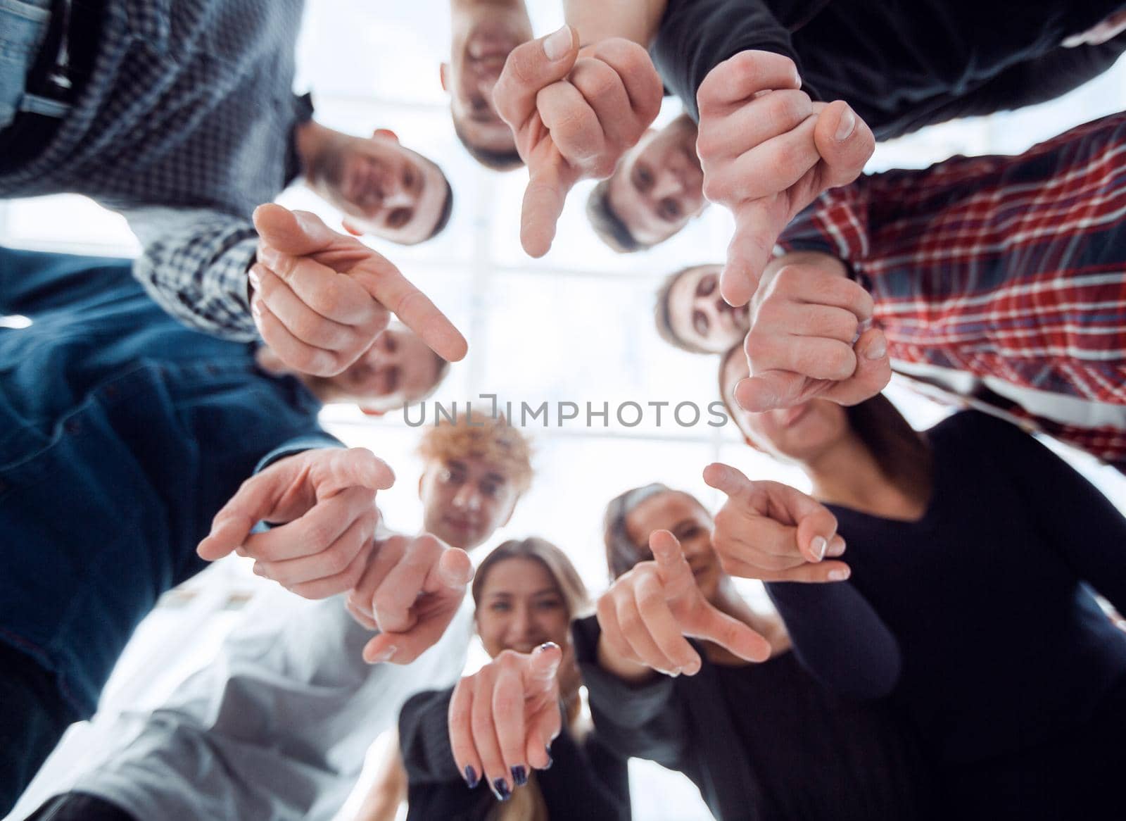 bottom view. ambitious young people standing in a circle and pointing at you. concept of choice