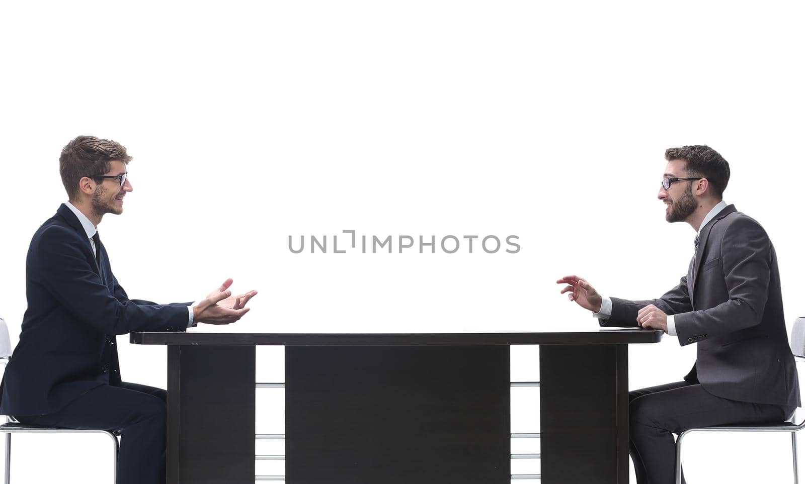 side view. two business people discussing something sitting at the table . isolated on white background