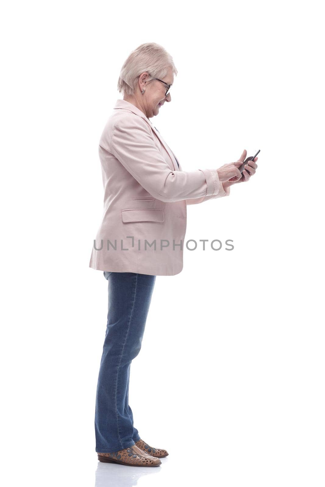 side view. cute senior woman talking on her smartphone . isolated on a white background