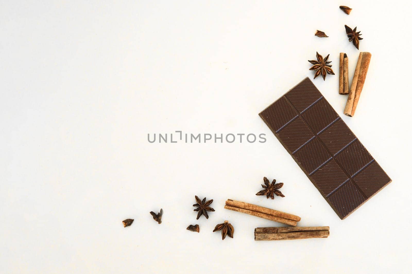 Milk chocolate and cinnamon sticks close-up on white background. Photos in warm colors. Sweetness. World chocolate day.