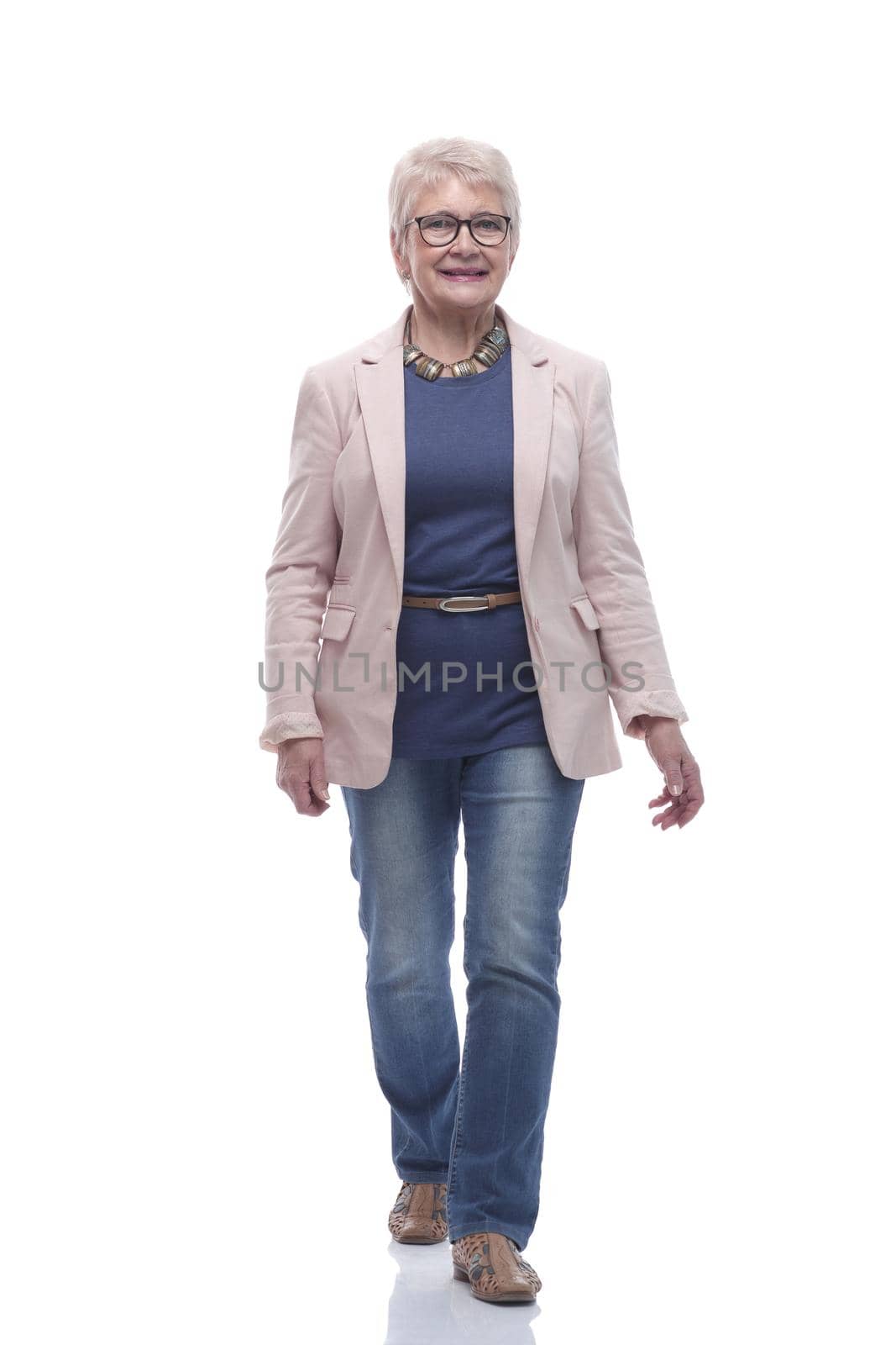 in full growth. confident senior woman goes forward . isolated on a white background
