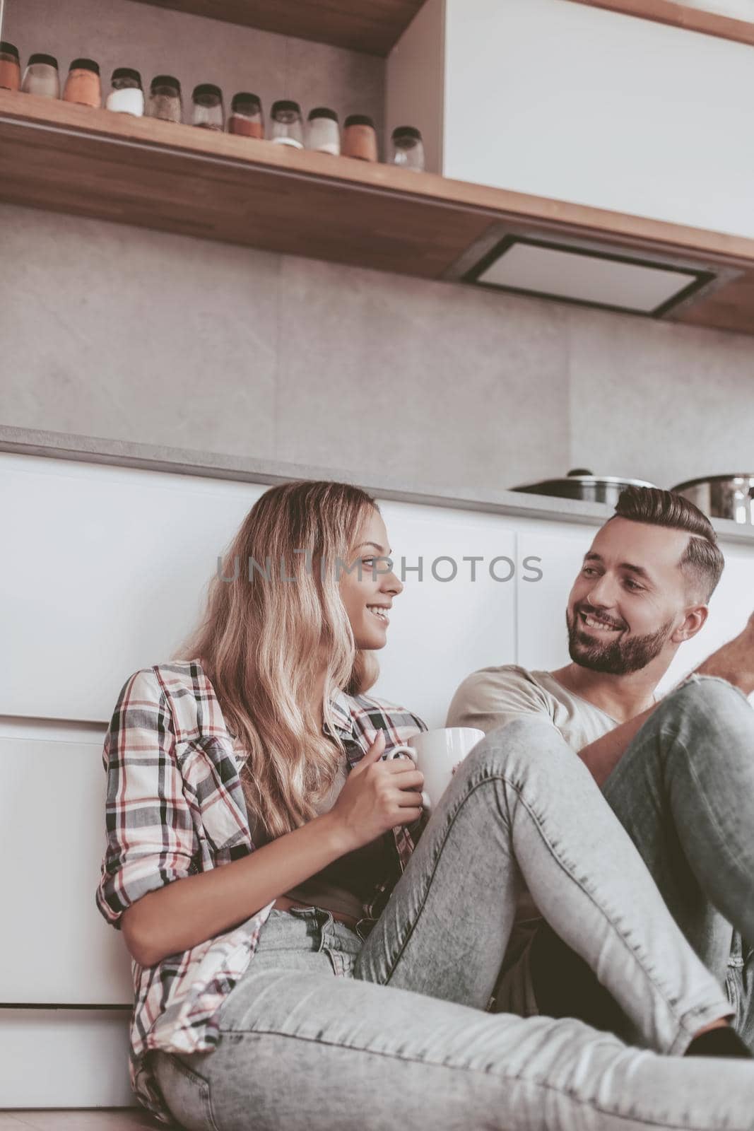 young couple drinking coffee sitting on the kitchen floor by asdf