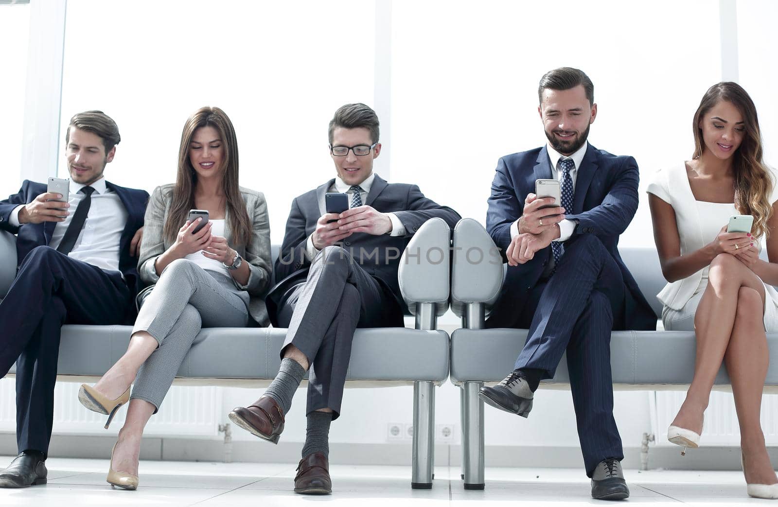 business colleagues with their smartphones sitting in the office hallway.people and technology