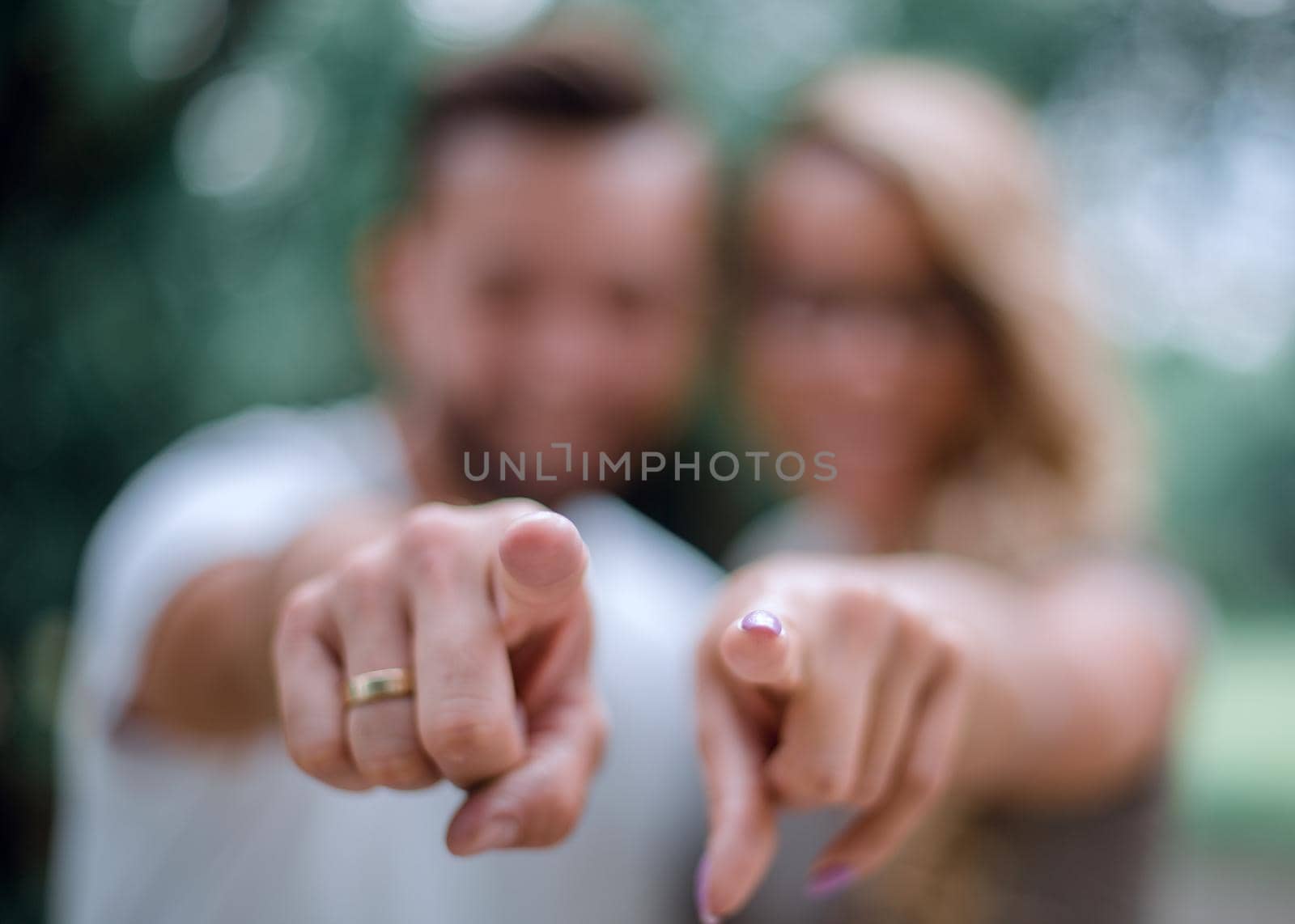 happy married couple standing in the Park and pointing at you. by asdf