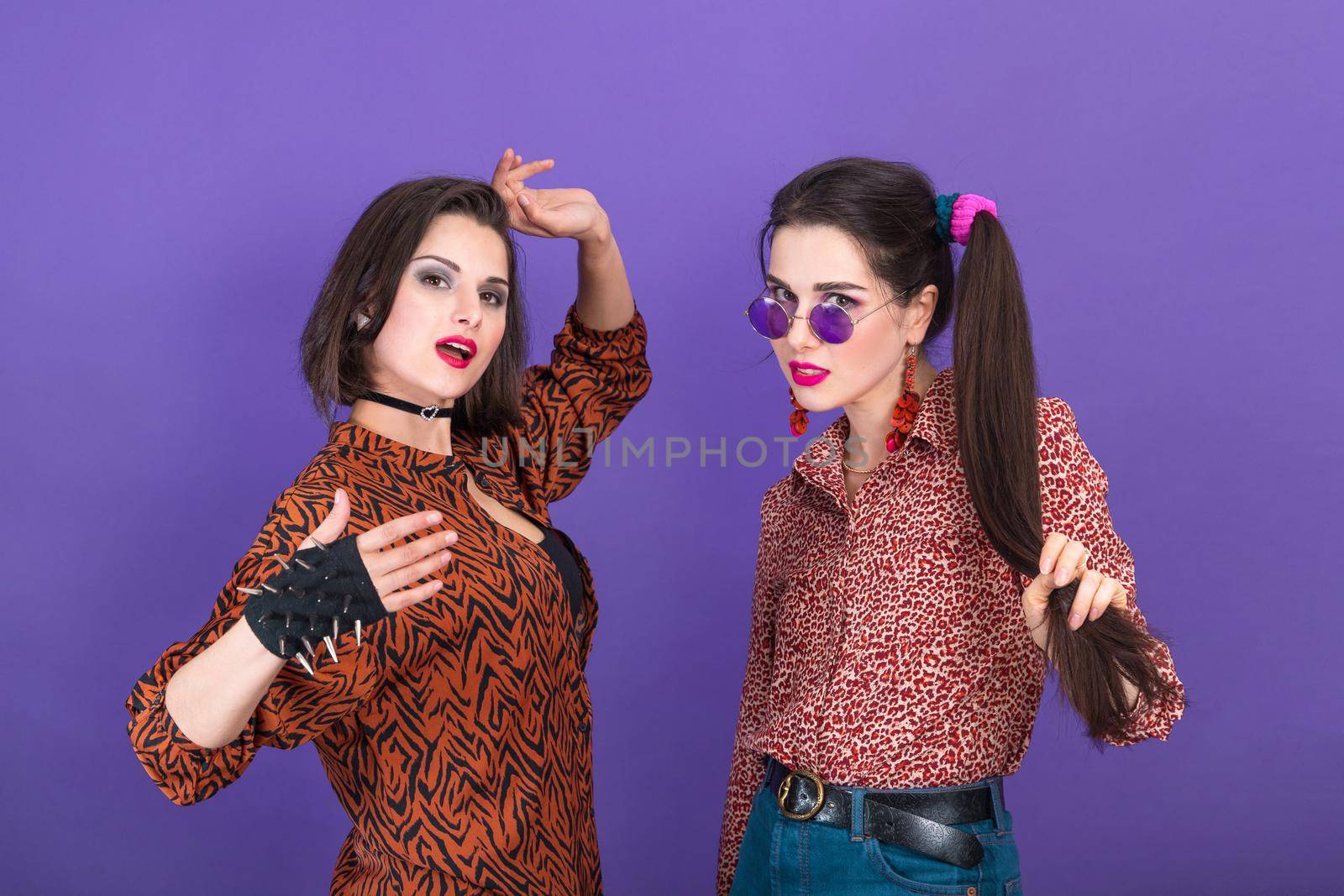 Two cute young women dressed in 80s style fooling around on violet background by Rom4ek