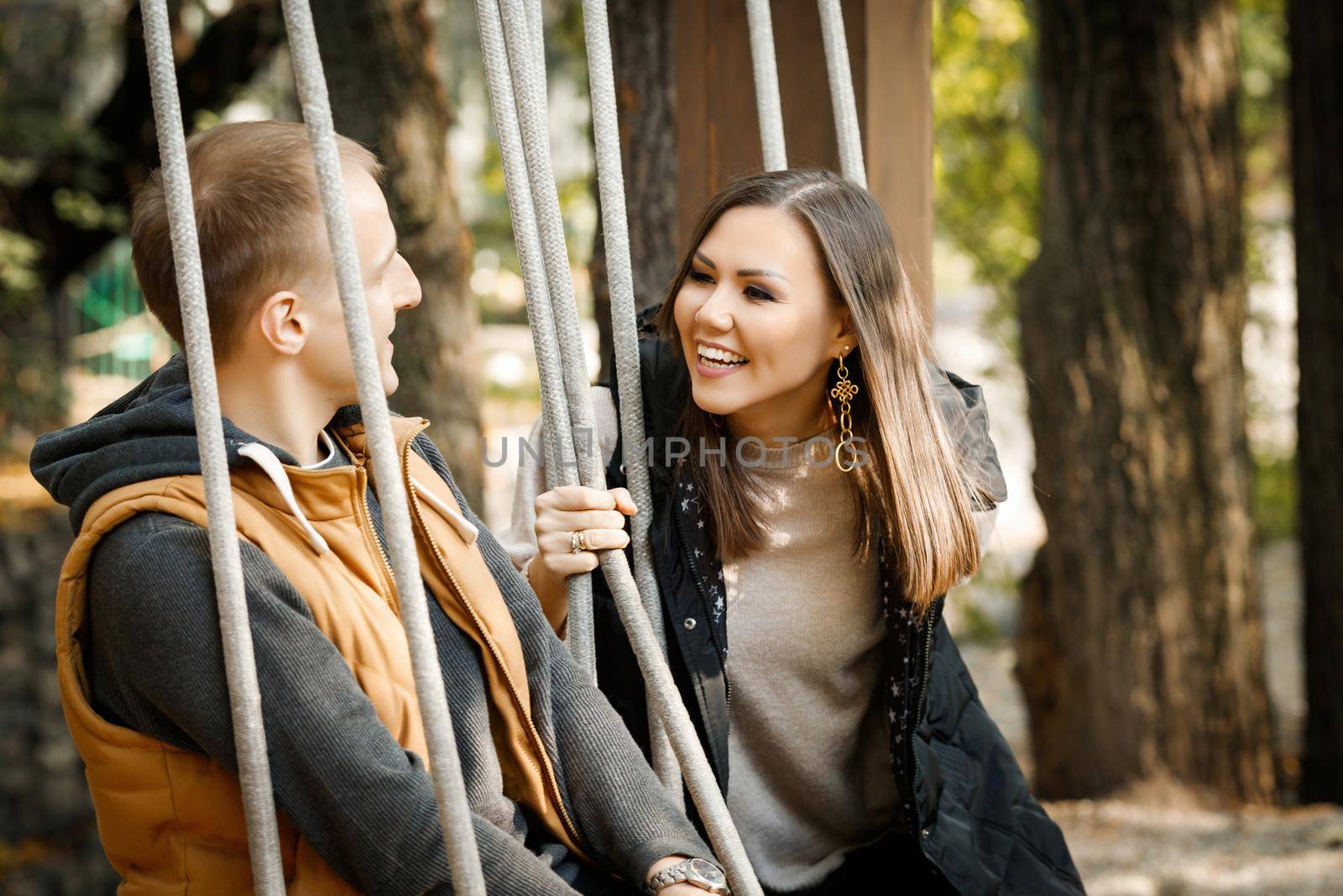 International happy couple in autumn in the park in the forest on a swing. High quality photo