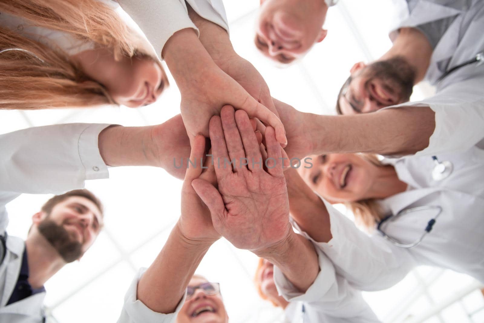close up. group of different doctors putting their hands together . concept of unity.