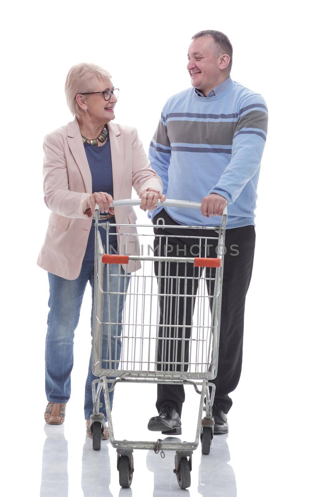 in full growth. happy married couple with shopping cart. isolated on a white background