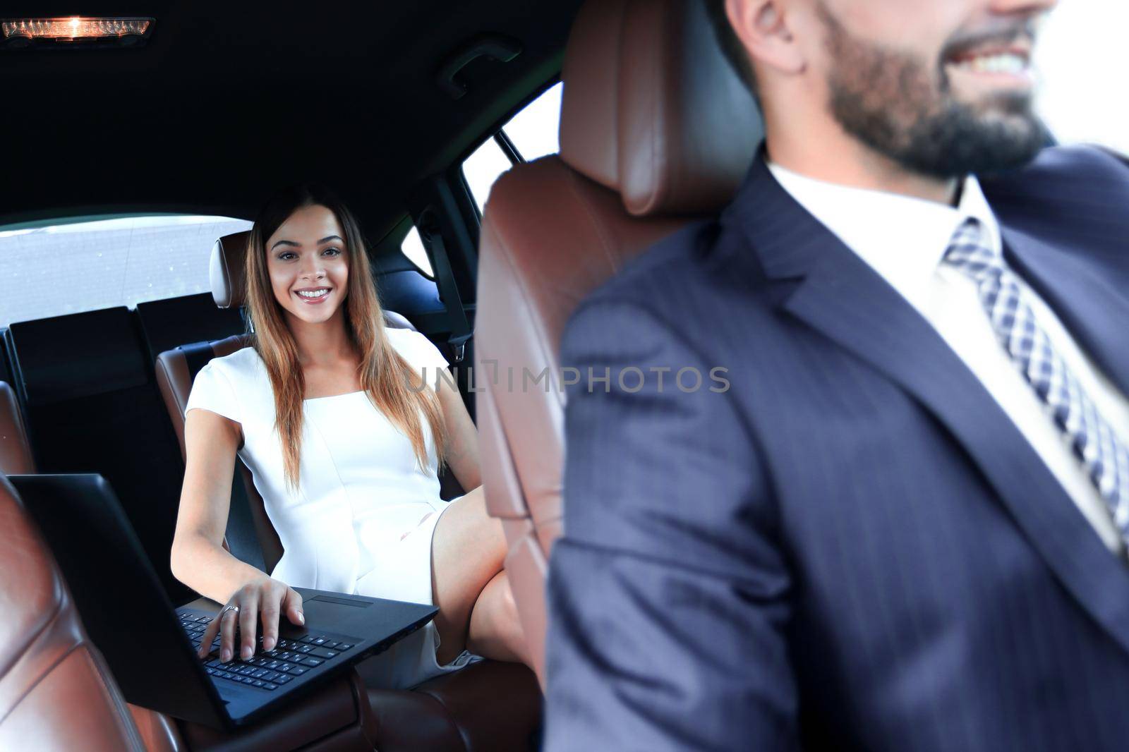 Female entrepreneur working during travelling to office in a luxury car.