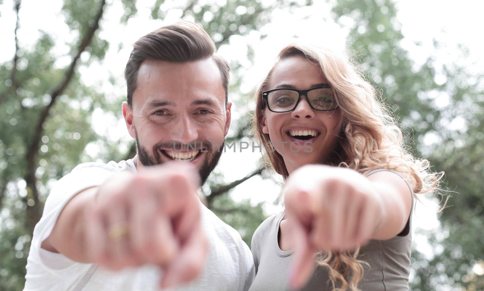 close up.happy newlyweds standing in the Park and pointing at you.photo with copy space