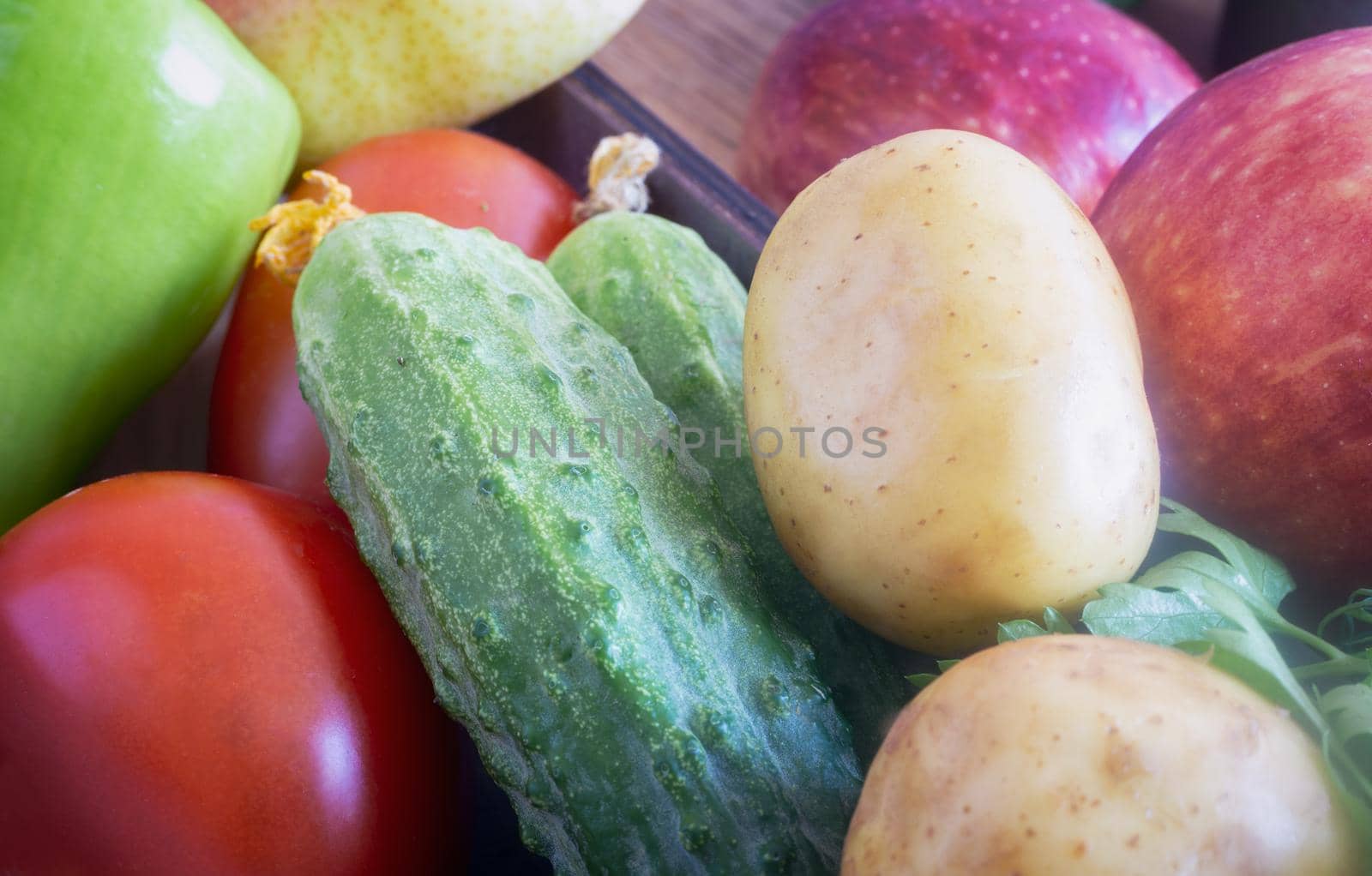 In a small box are cucumbers, tomatoes, apples. Presented in close-up.