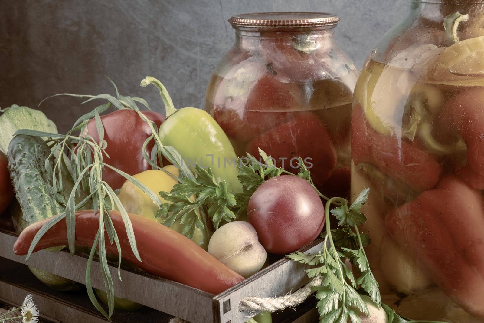 In glass jars, canned bell peppers, next to a box of peppers and other vegetables. Front view, close-up