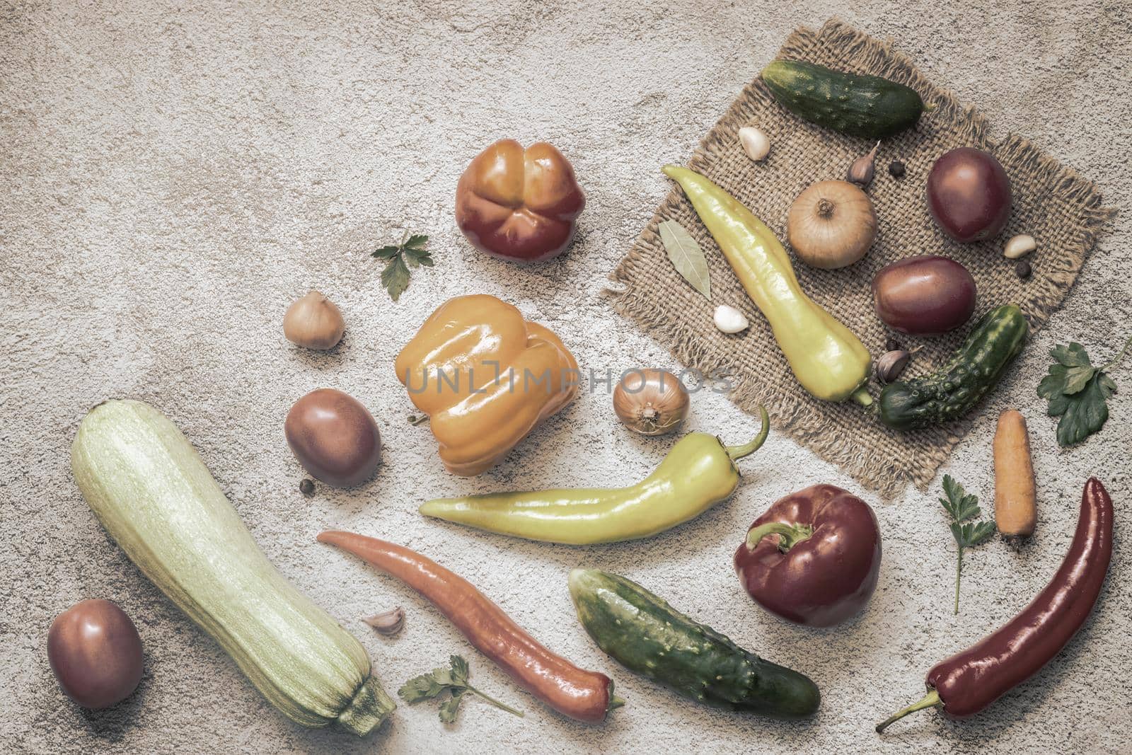 On the table and on a napkin a variety of ripe vegetables: tomatoes, peppers, cucumbers, parsley, zucchini. Top view with copy space. Flat lay