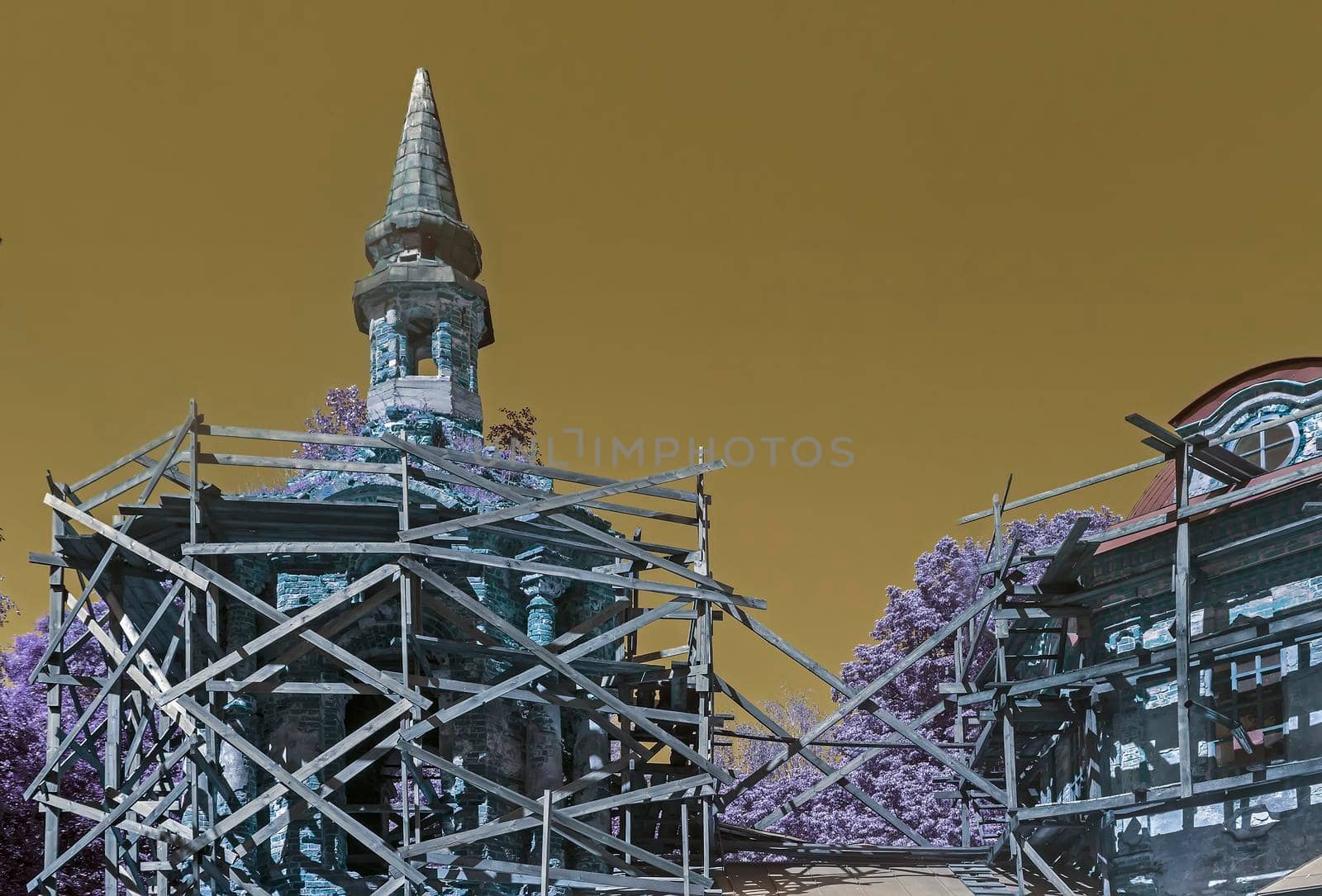 A small Orthodox old Church in the countryside is surrounded by scaffolding and restoration works are carried out.