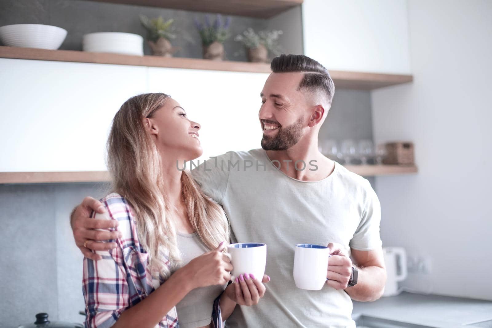 young couple drinking coffee standing in the kitchen by asdf