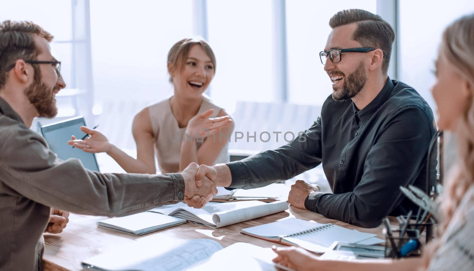 smiling business partners shaking hands at a business meeting. by asdf