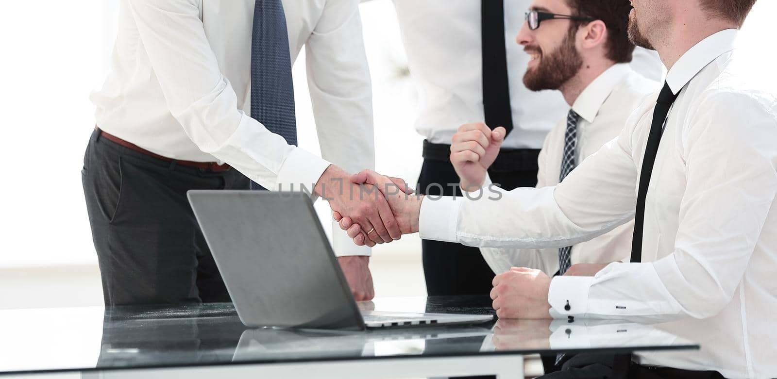 employees congratulating their colleague near the desktop by asdf