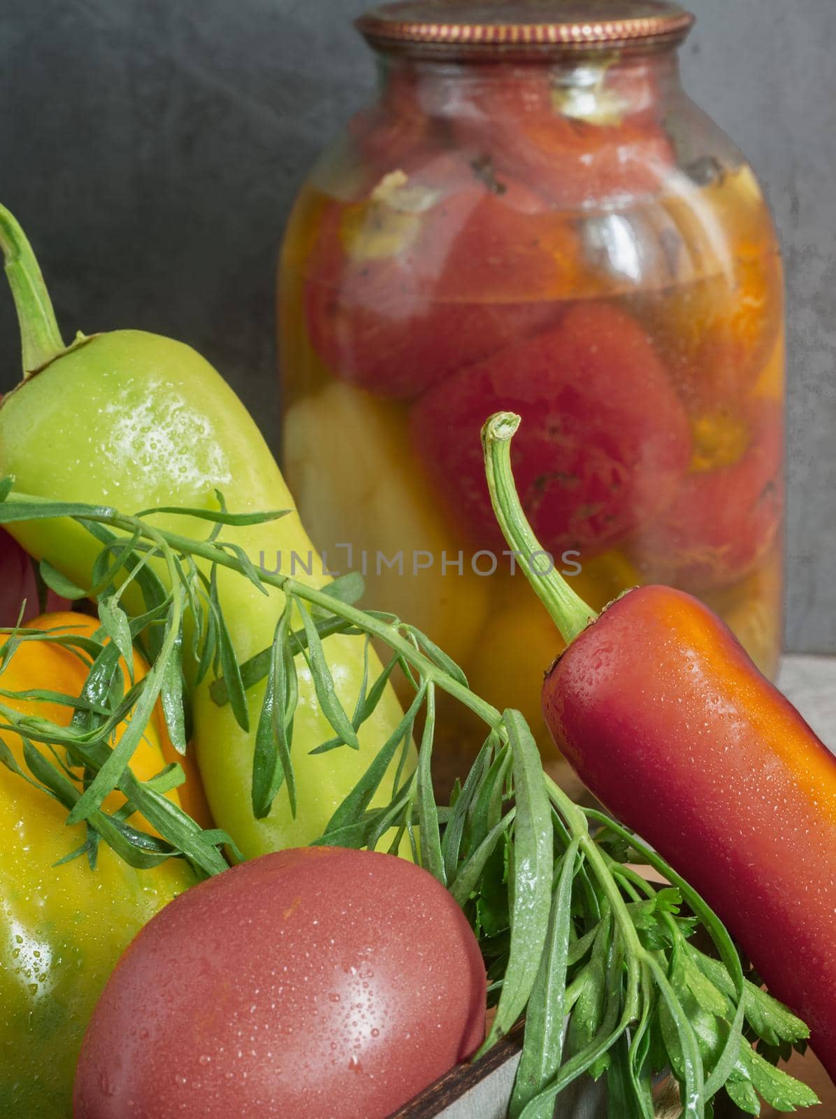 In glass jars, canned bell peppers, next to a box of peppers and other vegetables. Front view, close-up