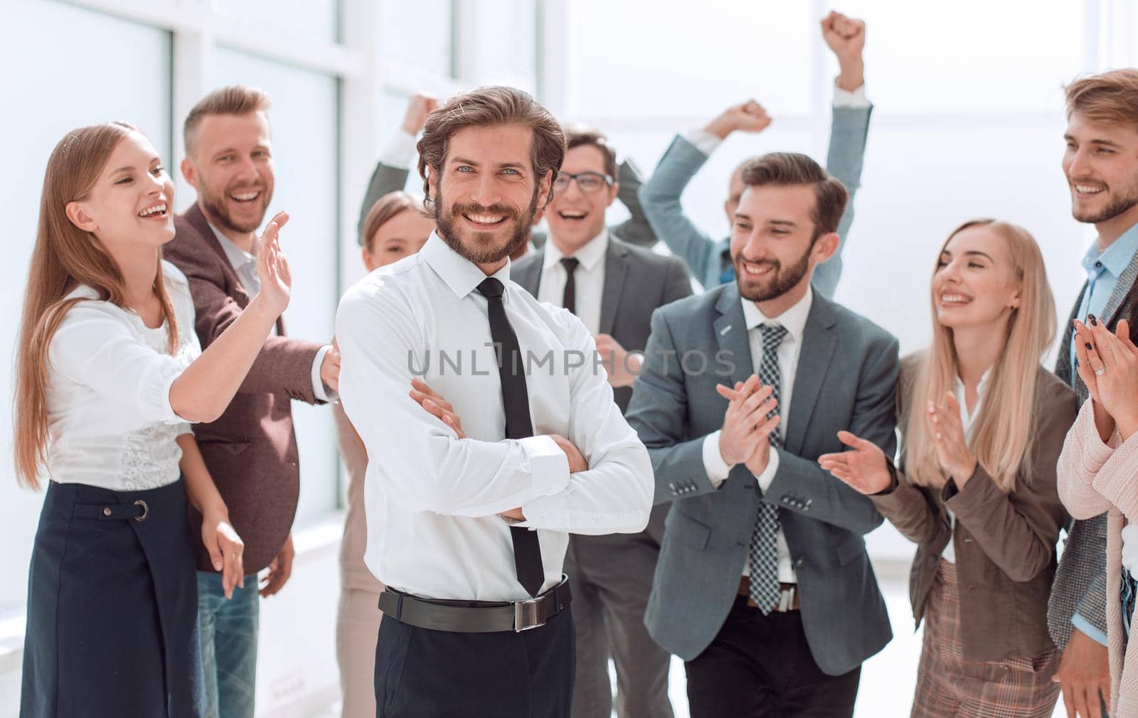 confident young businessman standing in front of a happy business team . success concept