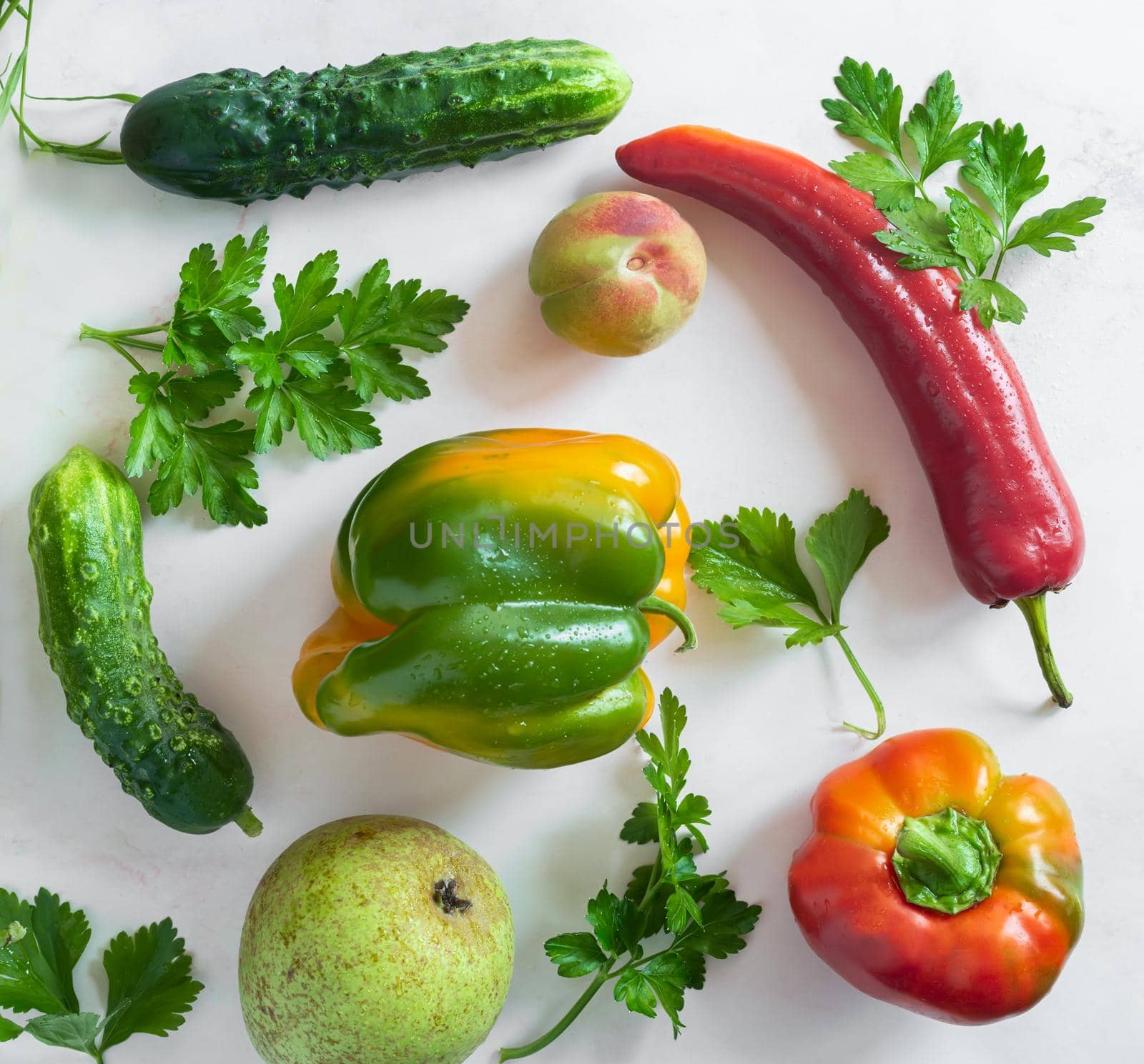 On the table and on a napkin a variety of ripe vegetables: tomatoes, peppers, cucumbers, parsley, zucchini. Top view with copy space. Flat lay