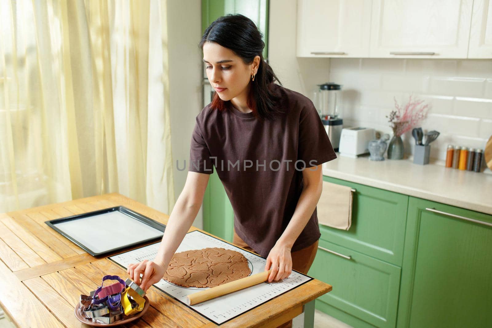 Young happy mixed race brunette woman cooking holiday homemade cookies.