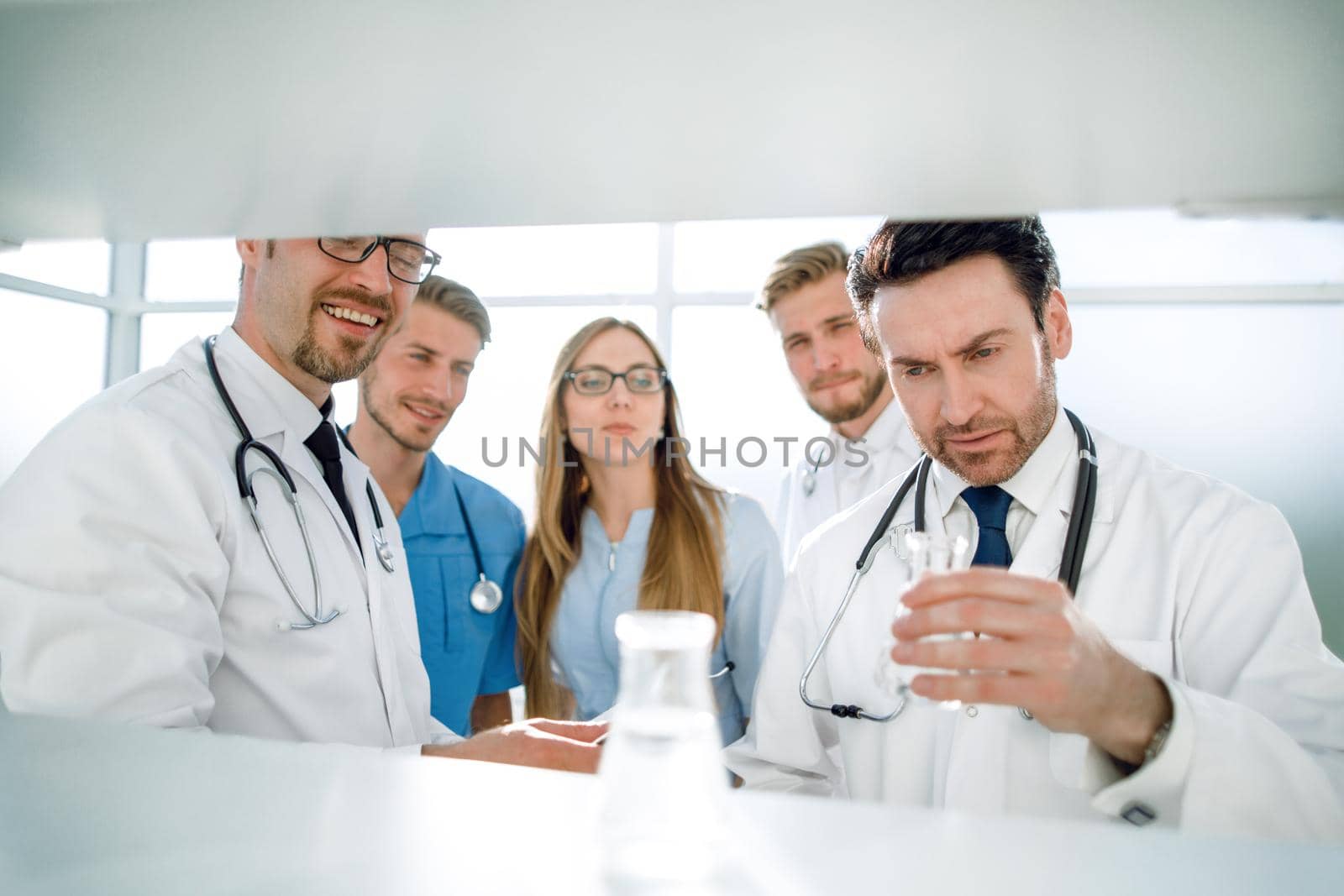 the doctor in holds a flask with transparent liquid close-up