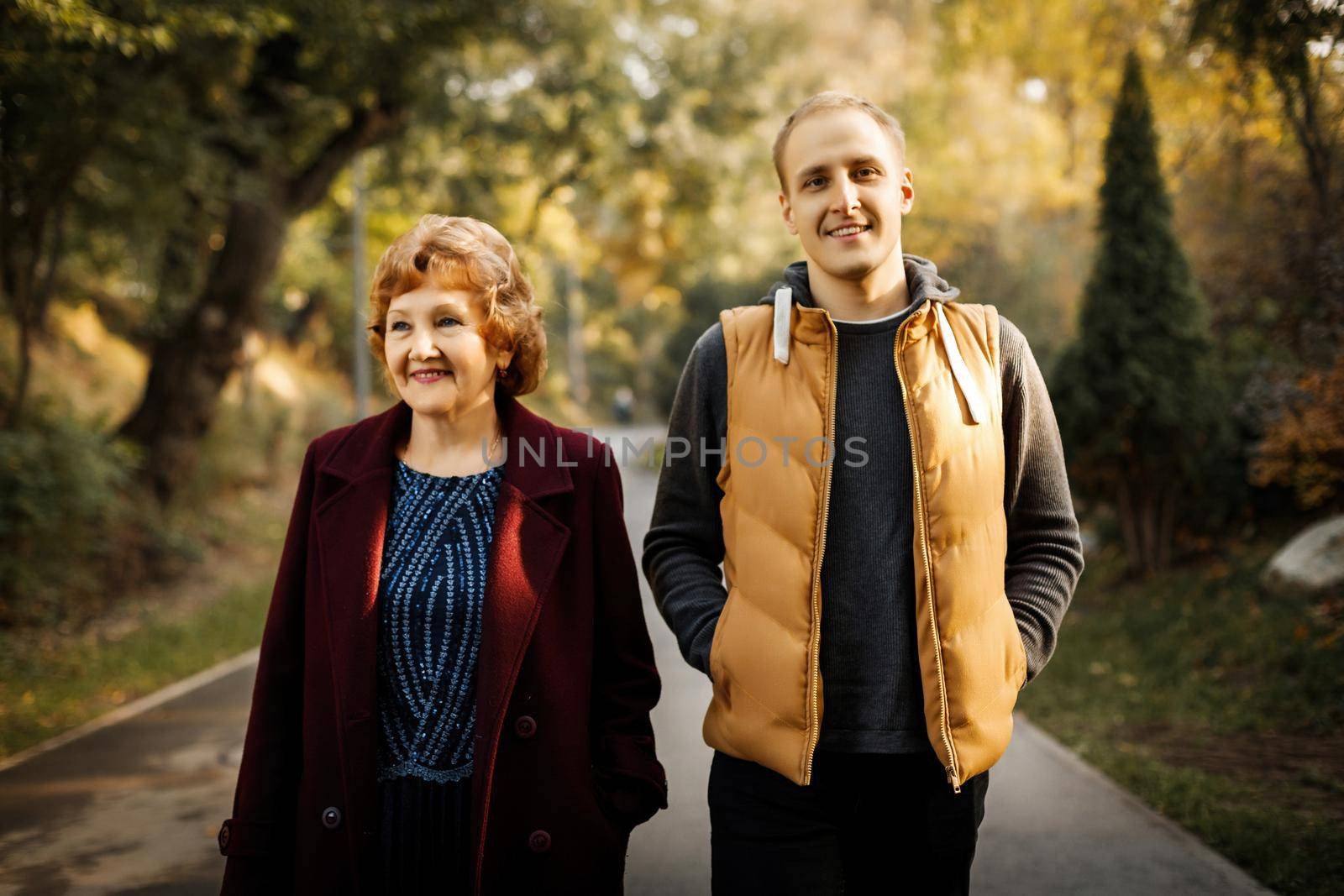 Happy mom with adult son stand in the middle of the park among the trees outdoors. High quality photo