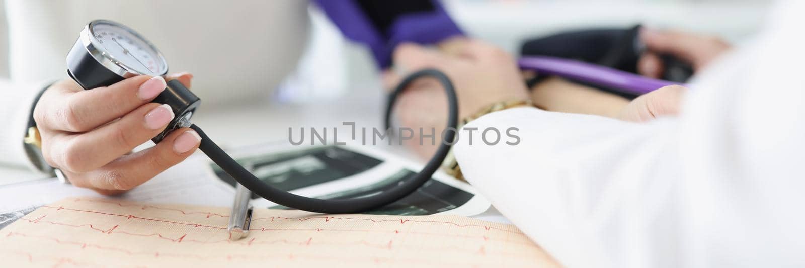 Close-up of female hand holding tonometer. Practitioner examining patient and measuring blood pressure. Doctors consultation idea. Healthcare and medicine concept