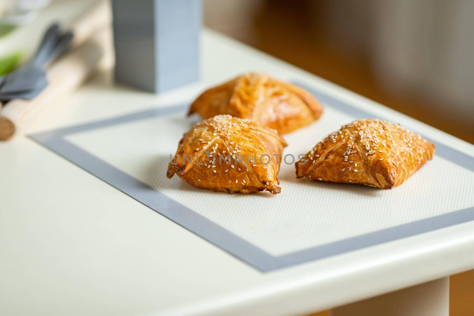 Fresh samsa on a baking mat on the kitchen table.